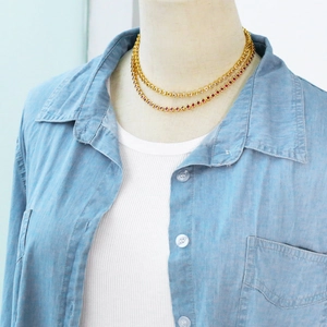 Close-up of layered gold chain necklace featuring red and white pave-set cubic zirconia stones
