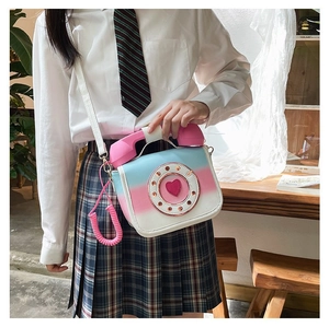 Detail of quirky pink and blue gradient telephone-shaped crossbody bag with heart dial