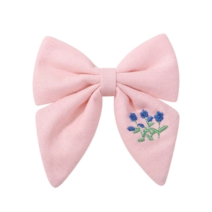 Gros plan sur un nœud papillon en tissu rose avec broderies florales bleues détaillées