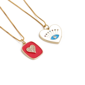 Gold plated necklaces with red heart zircon and white evil eye enamel pendants on white background