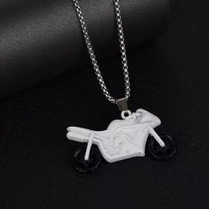 Close-up of a vintage punk motorcycle pendant with silver chain and black wheels