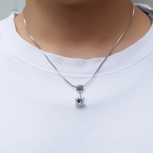 Silver turtle pendant necklace with a blue evil eye stone worn by a model on a white shirt