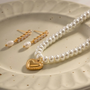 Elegant pearl necklace set with golden heart pendant and matching rhinestone earrings