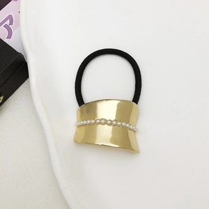 Macro shot of minimalist black hair tie with curved gold alloy bar and pearl details