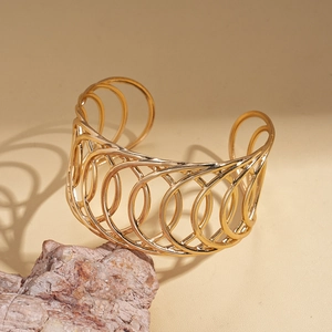 Vue détaillée du bracelet jonc doré à anneaux géométriques creux sur une pierre