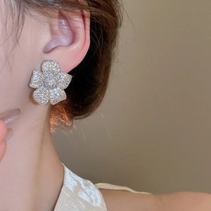 Detail view of sparkling zircon flower stud earring worn on model's ear for elegant style