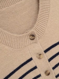 Close-up of oatmeal striped knit sweater featuring round neckline and amber texture buttons
