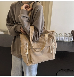 Gros plan du sac cabas en velours côtelé kaki montrant le tissu doux et les poches de rangement