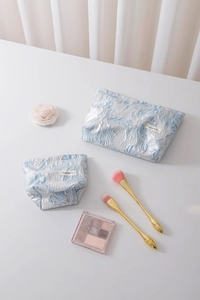 Detail of floral embossed jacquard makeup bags with large and small size set in blue and white