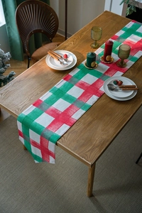 Detail of red and green plaid table runner with double-layer fabric on a wooden table