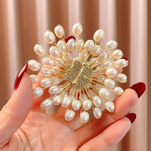Detailed macro of handmade gold wire woven brooch with natural freshwater white pearls
