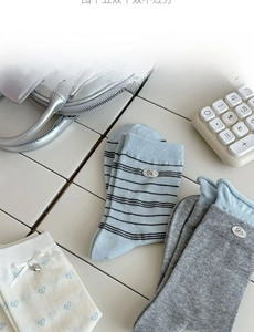 Detail of stylish crew socks featuring blue stripes and heart patterns on white tile