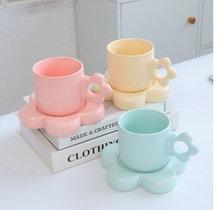 Macro detail of ceramic coffee cups featuring unique flower-shaped handles and saucers