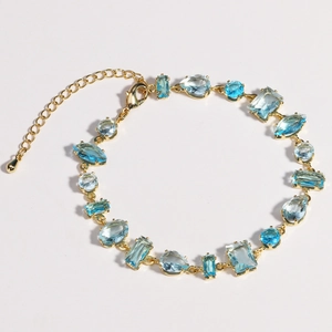 Detailed view of irregular blue zircon sugar cube bracelet with gold chain and gems