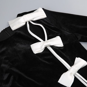 Detail of white bows on black velvet dress with cutout design and invisible zipper