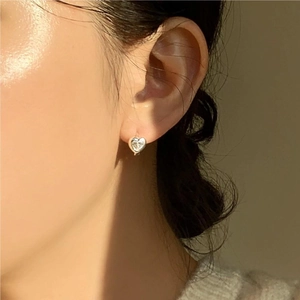 Close-up of minimalist heart-shaped silver earrings with sparkling cubic zirconia on model