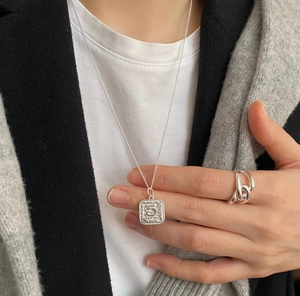 Close-up of a 925 sterling silver square coin necklace worn with a cable chain