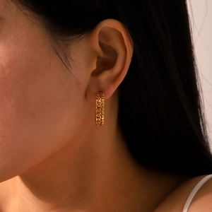 Detailed side view of gold geometric C-shaped hoop earrings with woven texture on model