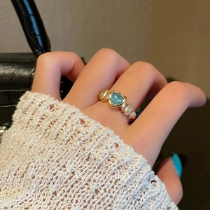 Vintage heart opal ring with gold band and zircons worn on a hand against elegant outfit