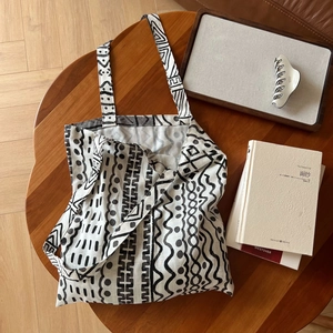 Gros plan d'un sac cabas en lin bohème aux motifs géométriques sur table en bois