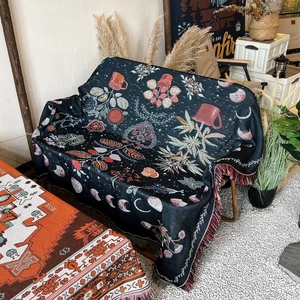 Bohemian camping blanket with lunar phase jacquard pattern and tassel edges on a chair