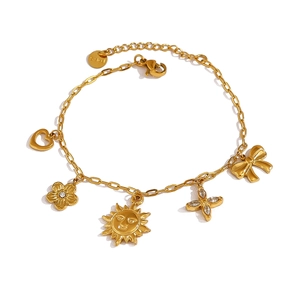 Bracelet doré en acier inoxydable avec breloques cœur, soleil et fleur sur fond blanc