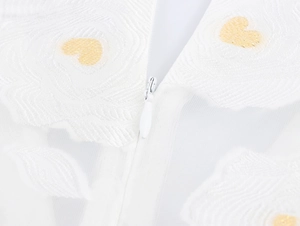 Close-up of invisible zipper on white floral jacquard dress with gold heart embroidery