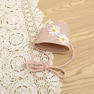 Close-up of pink woven crossbody bag for kids featuring delicate white daisy flower charms