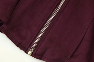 Macro shot of gold metal zipper and burgundy faux suede texture on a chic jacket