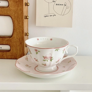 Close-up of floral ceramic coffee cup with pink roses and Rose text detail