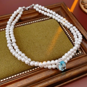 Collier double rang de perles avec pendentif zircon bleu clair sur support en velours