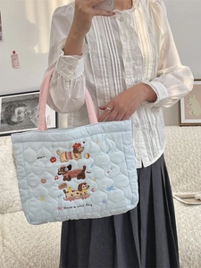 Sac fourre-tout matelassé bleu clair avec broderie de chien et poignées roses sur modèle