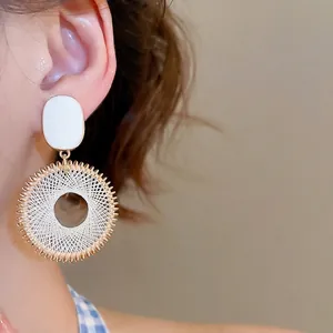 Bohemian dreamcatcher style gold circular drop earrings worn by a model in warm light