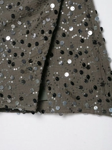 Vista macro di ricami con paillettes verde oliva su tessuto strutturato di alta qualità