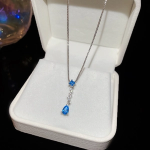 Close-up of square and teardrop aquamarine zircons on a silver chain in a jewelry box