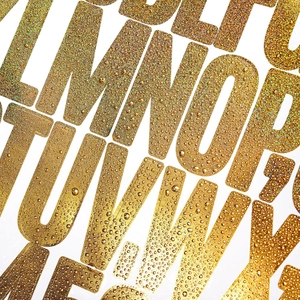 Macro detail of 2-inch gold glitter alphabet stickers with 3D water drop texture