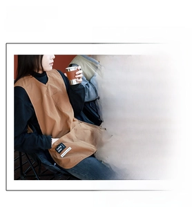 Detail of water-repellent brown nylon apron with V-neck design and functional large side pocket