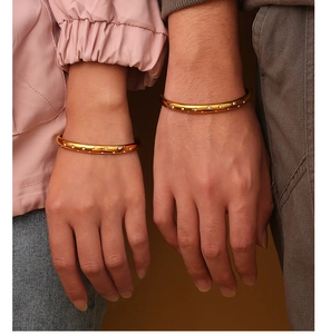 Detailed close-up of matching gold twisted couple bracelets with pavé diamond accents
