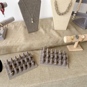Detailed jewelry display setup with grey velvet ring slots and beige linen necklace stands