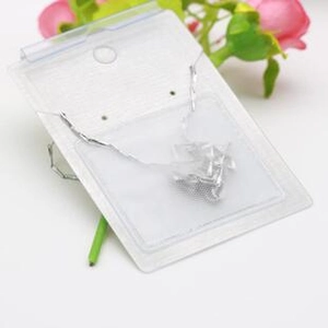 Silver necklace accessory in a clear plastic bag with white cardboard holder