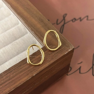 Detailed view of gold irregular geometric sterling silver studs on a wooden jewelry display
