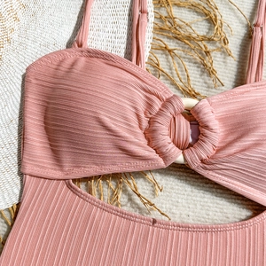 Détail d'un maillot de bain côtelé rose avec boucle ronde en bois et tissu texturé
