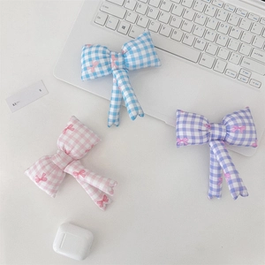Close-up of three cute pastel plaid bow hair clips in pink, blue, and purple colors