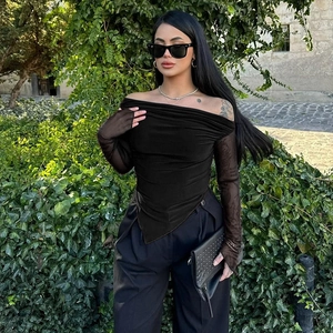 Detail of elegant black off-shoulder top featuring sheer mesh sleeves and asymmetric hemline