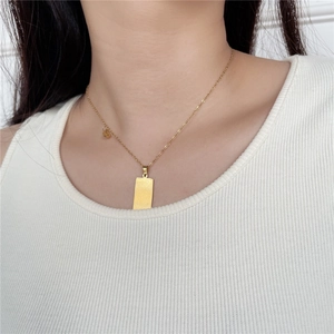 Detail of a gold Gemini tarot card necklace on model with engraved rectangle pendant