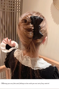 Macro shot of a large black fabric bow hair claw clip styled on a traditional bun
