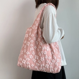 Detail of pink canvas tote bag with 3D white flower embroidery worn by a model