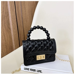 Detail of black jelly bag with quilted pattern, pearl handle and gold chain strap