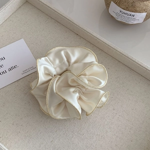 Gros plan du chouchou en satin crème avec bordure dorée sur un plateau décoratif