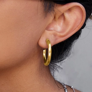 Close-up of 18K gold-plated stainless steel hollow hoop earrings worn by a model